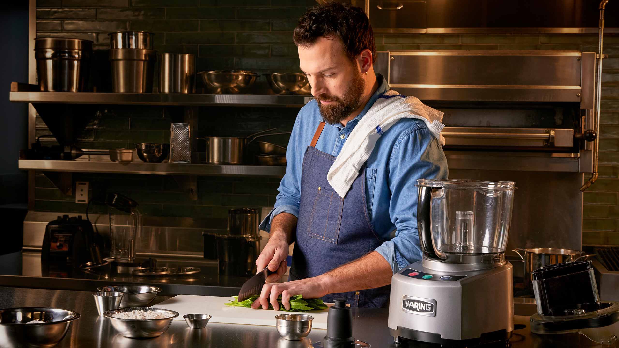 Chef cutting vegetables next to food processor | Waring